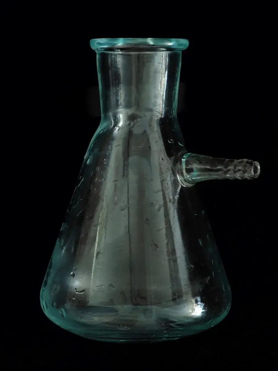 A heavy-wall filter flask with a side arm, against a black ground