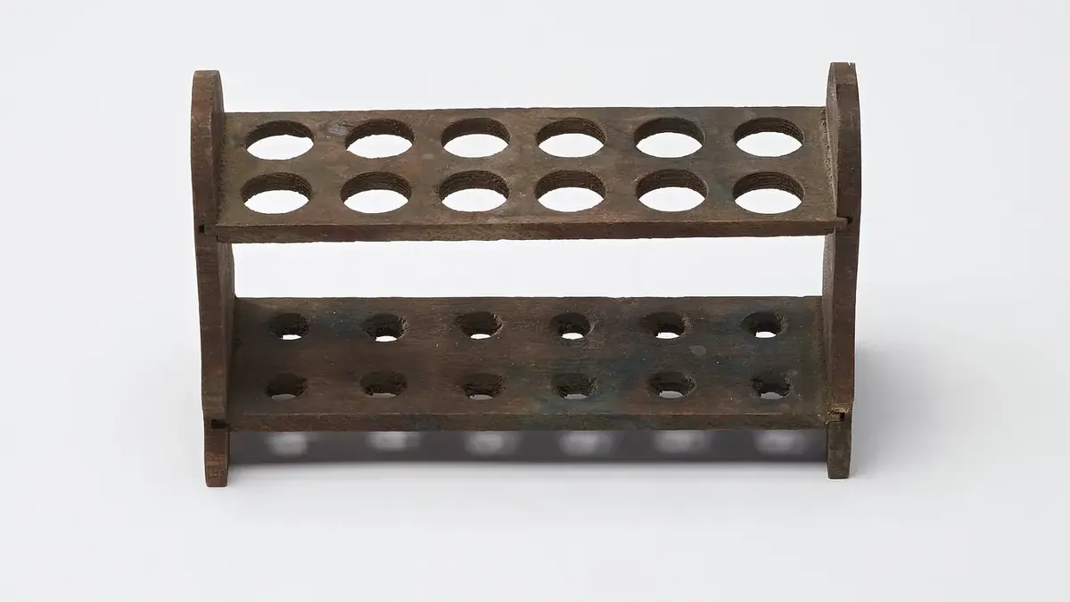 A two-tier wooden test-tube rack with drying pegs, photographed against white